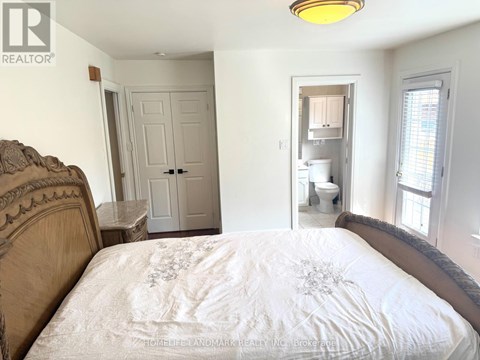 A bedroom with a bed, a toilet, and a sink in the background.