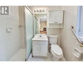A white bathroom with a toilet, sink, and shower.