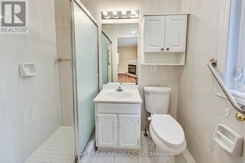 A white bathroom with a toilet, sink, and shower.