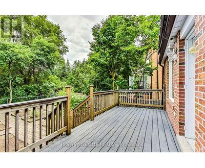 A wooden deck leads to a lush green backyard.