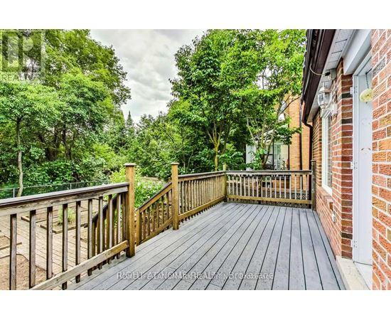 A wooden deck leads to a lush green backyard.