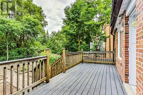 A wooden deck leads to a lush green backyard.
