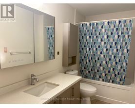 A bathroom with a sink, toilet, and shower curtain.