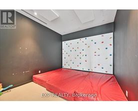 A room with a red bedspread and a wall with multicolored dots.
