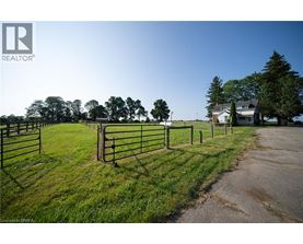 A fenced grassy area with a house in the background.