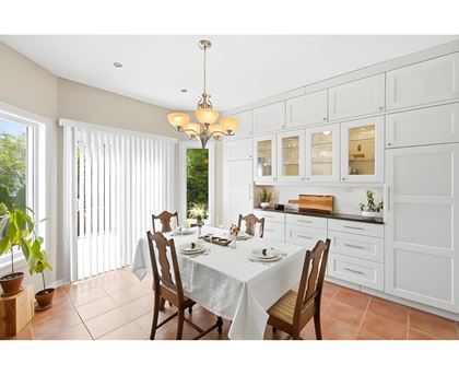 A dining room with a table set for two and a chandelier hanging from the ceiling.