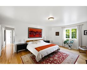 A bedroom with a large bed and a painting on the wall.