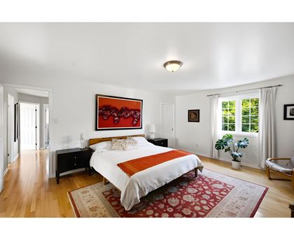 A bedroom with a large bed and a painting on the wall.