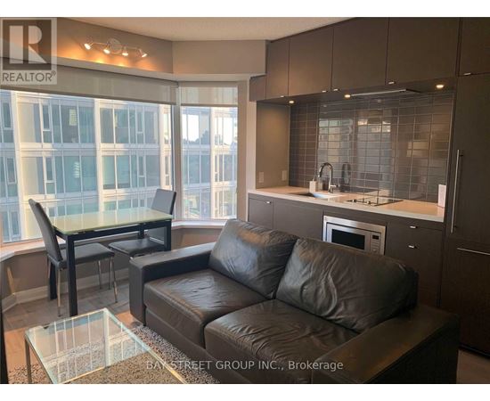 A modern living room with a glass table and leather couch.