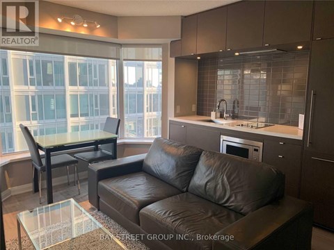 A modern living room with a glass table and leather couch.