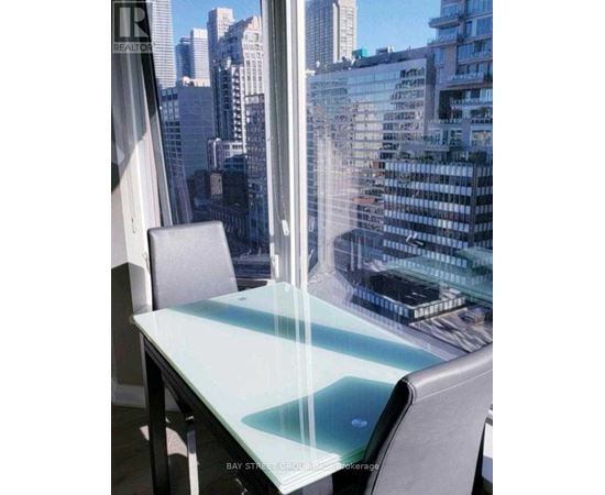 A glass table with a chair in front of a window overlooking a cityscape.