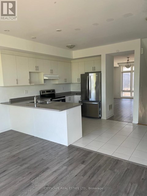 A modern kitchen with white cabinets and a wooden floor.