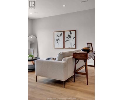 A living room with a couch, a chair, and a table with a plant on it.