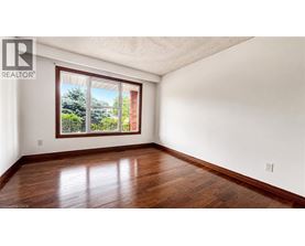 A room with a window showing a view of trees and a brick building.