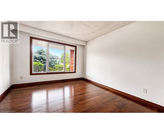 A room with a window showing a view of trees and a brick building.