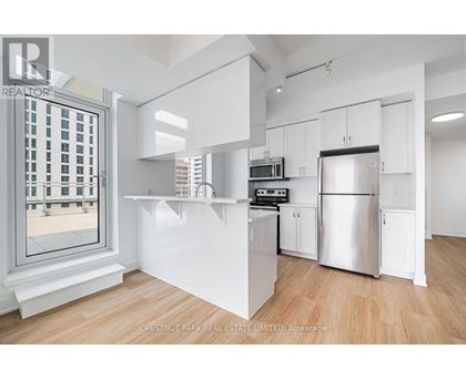 A modern kitchen with white cabinets and a stainless steel refrigerator.