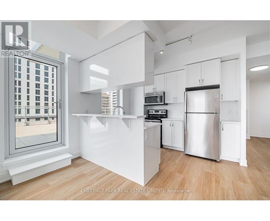 A modern kitchen with white cabinets and a stainless steel refrigerator.