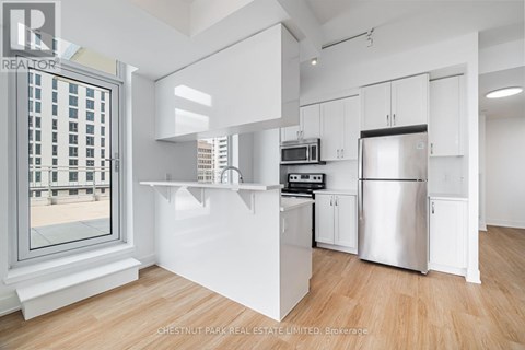 A modern kitchen with white cabinets and a stainless steel refrigerator.