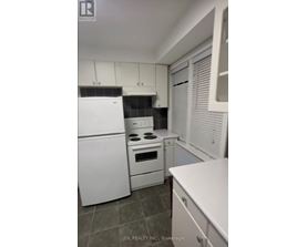 A white kitchen with a refrigerator, oven, and microwave.