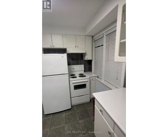 A white kitchen with a refrigerator, oven, and microwave.