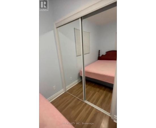 A bedroom with a pink bed and a mirror on the wall.