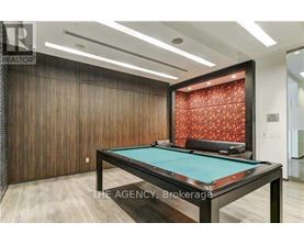A pool table in a room with wooden walls and a red patterned wallpaper.