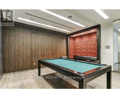 A pool table in a room with wooden walls and a red patterned wallpaper.