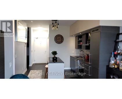 A modern kitchen with a bar area and a clock on the wall.