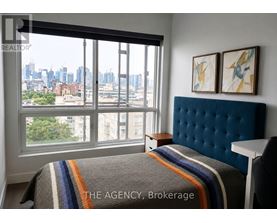 A bedroom with a large window overlooking a cityscape.