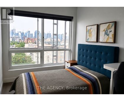 A bedroom with a large window overlooking a cityscape.