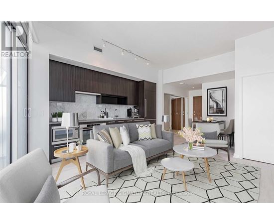 A modern living room with a grey sofa, a coffee table, and a kitchen area in the background.