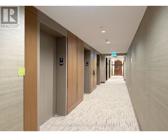 A hallway with a carpeted floor and doors on the left side.