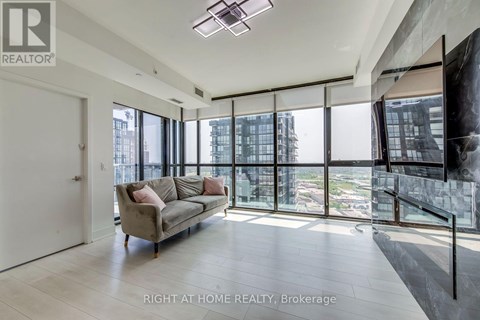 A spacious living room with a couch and a large window overlooking the city.