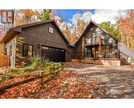 A house with a garage and a balcony is surrounded by fallen leaves.