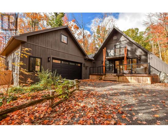 A house with a garage and a balcony is surrounded by fallen leaves.