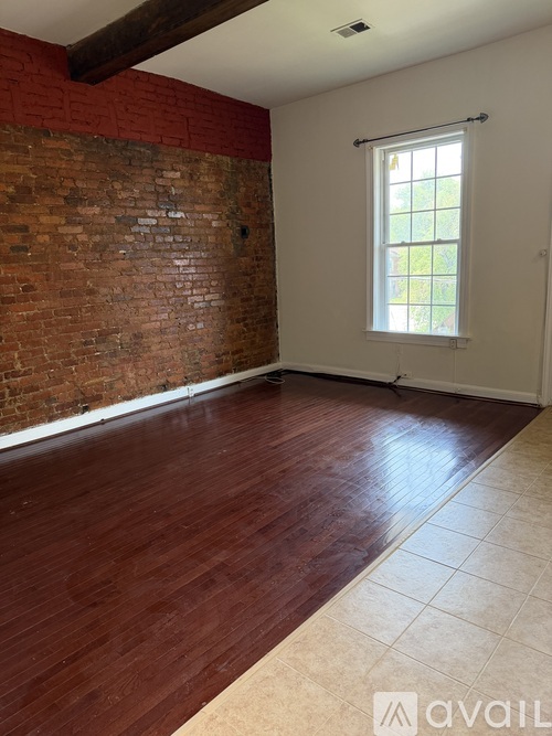 A room with a red brick wall and wooden flooring.
