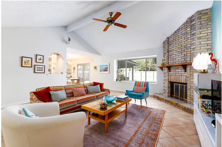 A living room with a white couch, a wooden coffee table, and a fireplace.