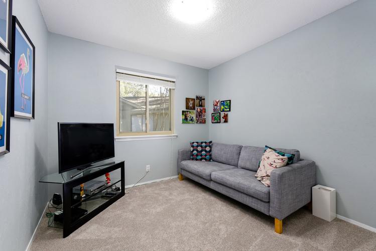 A living room with a grey couch and a black television.