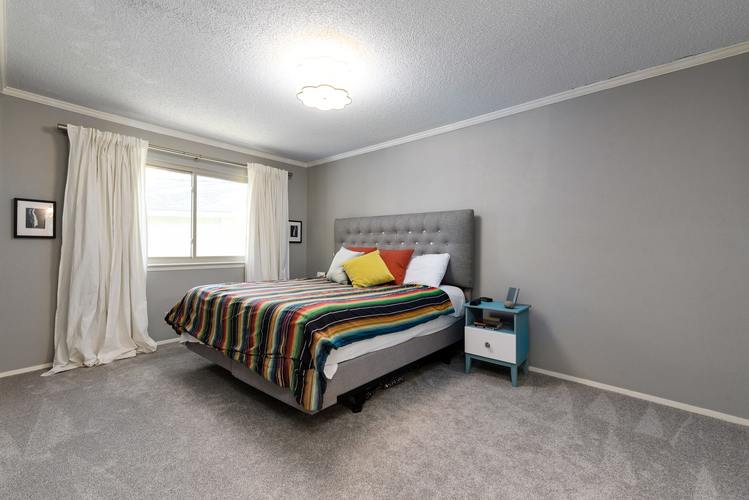 A bedroom with a bed, nightstand, and window.