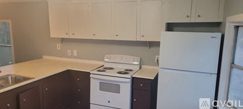 A kitchen with white cabinets and a white fridge.
