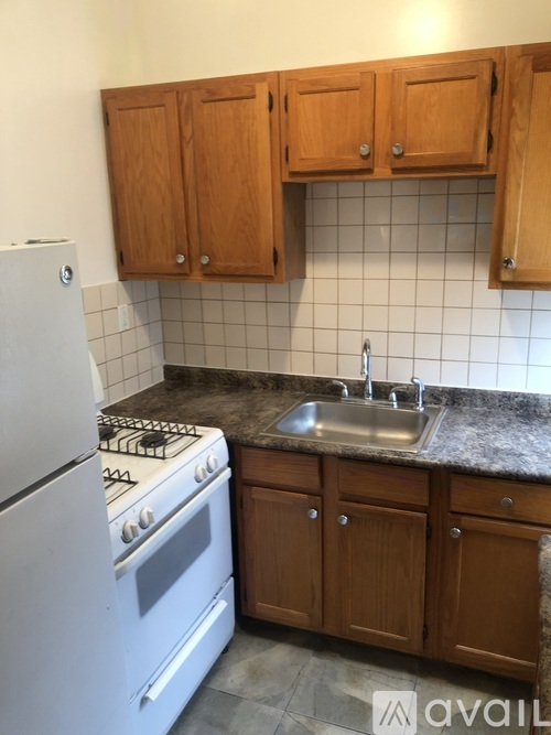 A kitchen with a white fridge, wooden cabinets, and a white stove top oven.