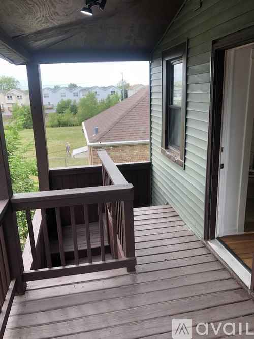 A wooden deck with a railing and a door leading to a house.