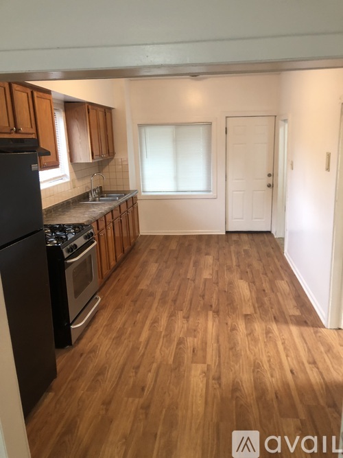 A kitchen with wooden floors and a black refrigerator.