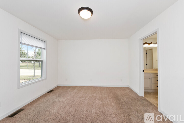 A room with a carpeted floor and a window overlooking a grassy area.