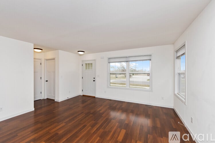 A spacious room with wooden floors and white walls.