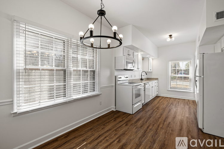 A kitchen with white appliances and wooden floors.