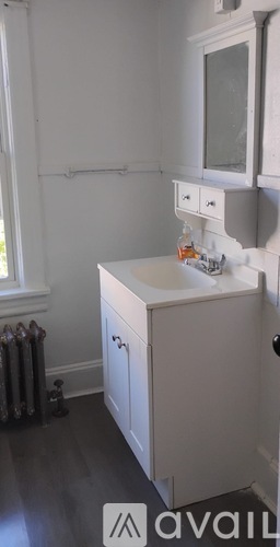 A white cabinet with a sink and a window in the background.