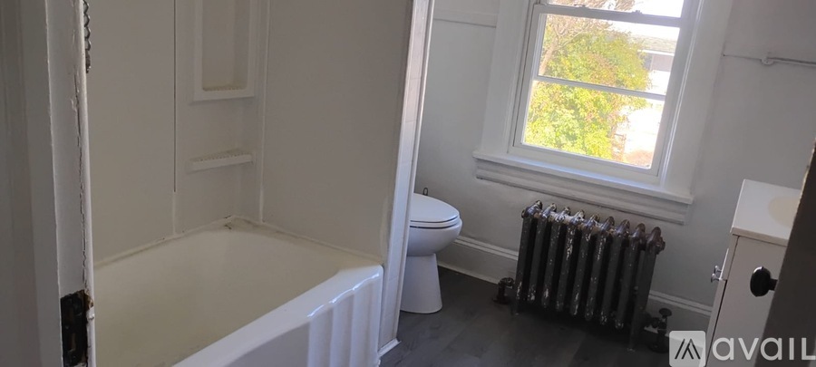 A bathroom with a toilet, a bathtub, and a radiator.