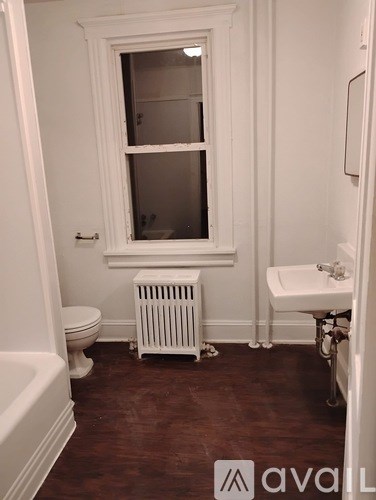 A white bathroom with a toilet, sink, and radiator.