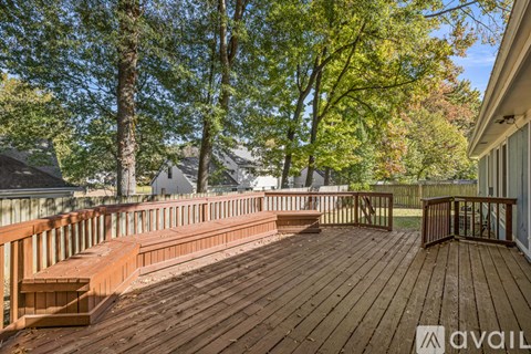 A wooden deck with a railing and a bench is surrounded by trees.